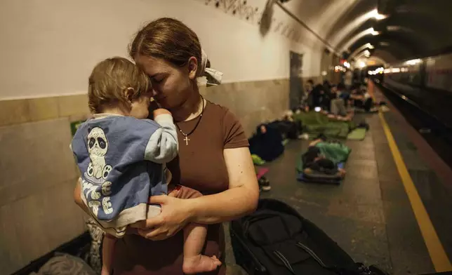 Oleksandra Umanets, 23, calms her 10-month-old son as they take cover on the platform of a metro station during a Russian attack on Kyiv, Ukraine, on Thursday, July 10, 2025. (AP Photo/Evgeniy Maloletka)