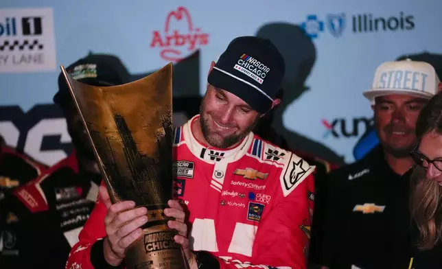 Shane van Gisbergen, center, holds the trophy after winning a NASCAR Cup Series auto race at the Grant Park 165, Sunday, July 6, 2025, in Chicago. (AP Photo/Erin Hooley)