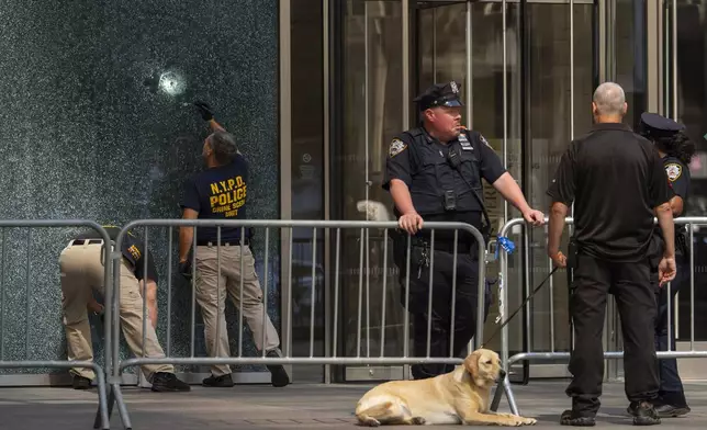 Members of the NYPD Crime Unit examine a door with bullet holes at the scene of the previous day's deadly shooting, Tuesday, July 29, 2025, in New York. (AP Photo/Yuki Iwamura)