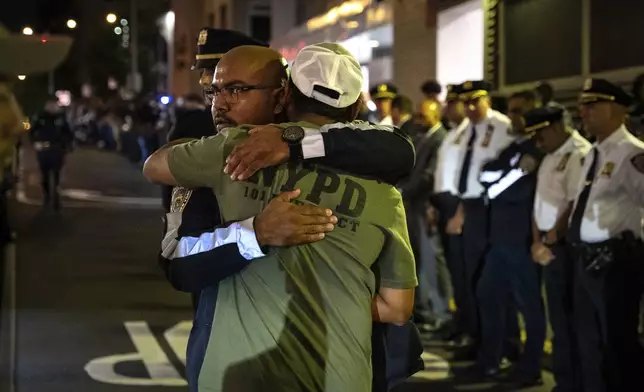 People embrace during the dignified transfer of Didarul Islam, who was shot and killed by a gunman earlier this evening, out of NewYork-Presbyterian/Weill Cornell Medical Hospital to the medical examiner's office, early Tuesday, July 29, 2025, in New York. (AP Photo/Angelina Katsanis)