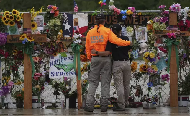 FILE - Members of a search and rescue team embrace as they visit a memorial wall for flood victims, Sunday, July 13, 2025, in Kerrville, Texas. (AP Photo/Eric Gay, File)