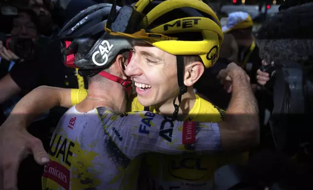 Tour de France winner Tadej Pogacar of Slovenia is hugged by a teammate after the twenty-first stage of the Tour de France cycling race over 132.3 kilometers (82.1 miles) with start in Mantes-la-Ville and finish on the Champs-Elysees in Paris, France, Sunday, July 27, 2025. (AP Photo/Mosa'ab Elshamy)
