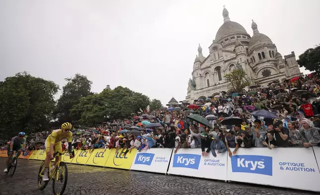 Slovenia's Tadej Pogacar, wearing the overall leader's yellow jersey, pedals by the Sacre Coeur basilica in the Montmartre district, during the last stage of the Tour de France cycling race between Mantes-la-Ville and Paris, Sunday, July 27, 2025 in Paris (AP Photo/Thomas Padilla)