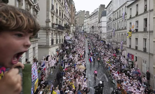 A boy shouts as the pack rides up the Montmartre hill during the last stage of the Tour de France cycling race between Mantes-la-Ville and Paris, Sunday, July 27, 2025 in Paris (AP Photo/Laurent Cipriani)