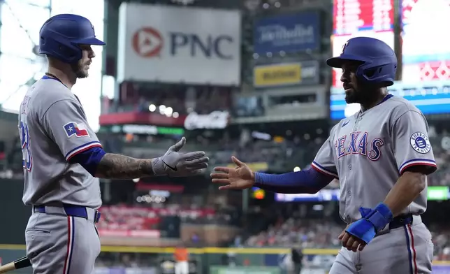 Texas Rangers' Jonah Heim, left, congratulates Marcus Semien, right, after he scored during the first inning of a baseball game against the Houston Astros, Friday, July 11, 2025, in Houston. (AP Photo/Kevin M. Cox)