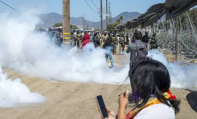Federal immigration agents toss tear gas at protesters during a raid in the agriculture area of Camarillo, Calif., Thursday, July 10, 2025. (AP Photo/Michael Owen Baker)