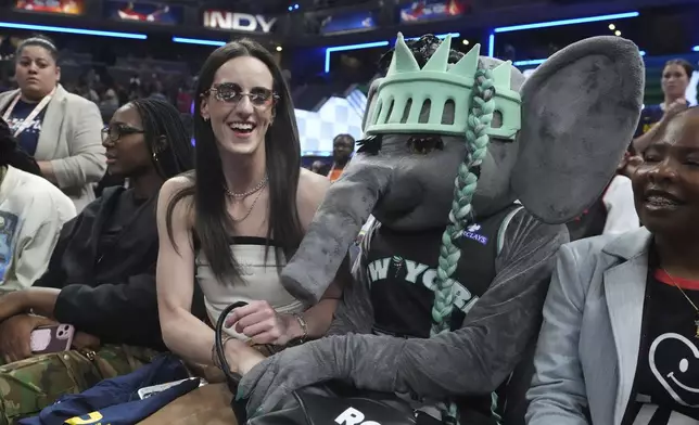 Indiana Fever's Caitlin Clark sits by the New York Liberty mascot during the skills challenge at the WNBA All Star events, Friday, July 18, 2025, in Indianapolis. (AP Photo/Michael Conroy)