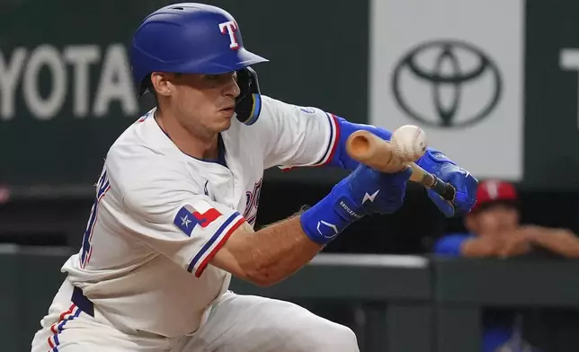 Texas Rangers Michael Helman connects for sacrifice bunt that scored teammate Josh Smith during the seventh inning of a baseball game against the Athletics, Monday, July 21, 2025, in Arlington, Texas. (AP Photo/LM Otero)