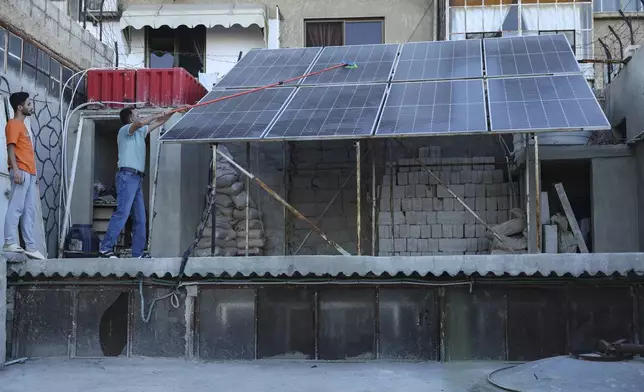 A Syrian man Abdul Razzaq Al-Jenan, cleans solar panels that set on his house roof, in Damascus, Syria, Sunday, June 29, 2025. (AP Photo/Ghaith Alsayed)