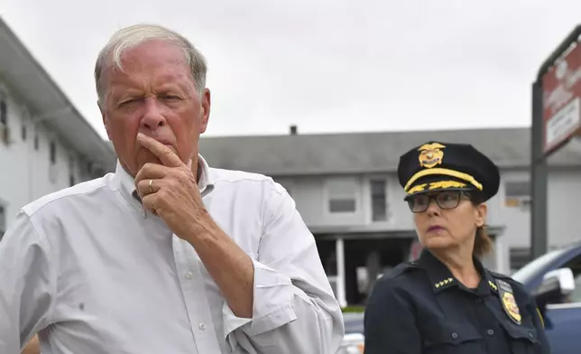 Fall River Mayor Paul Coogan, left, faces reporters near the Gabriel House assisted living facility, behind, Monday, July 14, 2025, following a fire at the facility that started late Sunday, in Fall River, Mass. (AP Photo/Steven Senne)