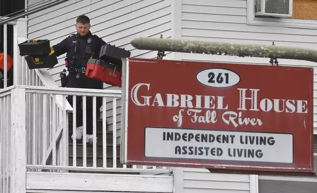 A law enforcement official removes boxes containing patient medications from the Gabriel House assisted living facility following a fire that resulted in multiple fatalities, in Fall River, Mass., Monday, July 14, 2025. (AP Photo/Steven Senne)