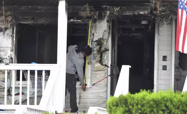 An investigator takes measurements Monday, July 14, 2025, near an entrance to the Gabriel House assisted living facility following a fire that started late Sunday in Fall River, Mass. (AP Photo/Steven Senne)