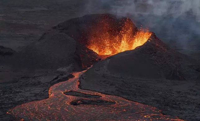 A lava flow is seen at the base of the crater, background, which is still very active after a volcanic eruption around 6km north of Grindavik on the Reykjanes Peninsula, in Iceland, Wednesday, July 23, 2025. (AP Photo/Marco di Marco)