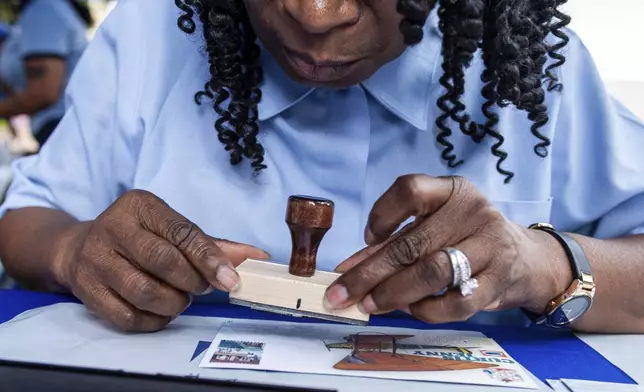 A U.S. Postal worker applies a First Day of Issue stamp on an envelope during the U.S. Postal Services event to mark their 250th anniversary, Wednesday, July 23, 2025, in Washington. (AP Photo/Cliff Owen)