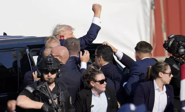 FILE - Republican presidential candidate former President Donald Trump is escorted to a motorcade following an attempted assassination at a campaign event in Butler, Pa., July 13, 2024. (AP Photo/Gene J. Puskar, File)