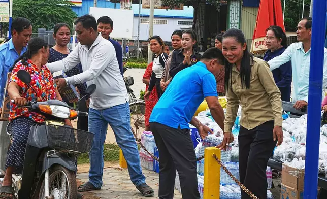 A Cambodian youth volunteer Chhar Sin, front right, welcomes villagers who donate their personal belongings for the displacing people at a sidewalk in Srey Snam district in Siem Reap province, Cambodia, Saturday, July 26, 2025, during fighting between Thailand and Cambodia. (AP Photo/Heng Sinith)