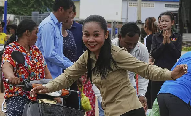 A Cambodian youth volunteer Chhar Sin, foreground, greats villagers who donate their personal belongings for the displacing people at a sidewalk in Srey Snam district in Siem Reap province, Cambodia, Saturday, July 26, 2025, during fighting between Thailand and Cambodia. (AP Photo/Heng Sinith)