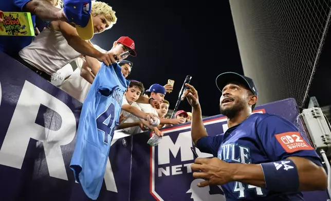 Seattle Mariners Julio Rodríguez, right, greets fans after winning a baseball game against the Los Angeles Angels Thursday, July 24, 2025, in Anaheim, Calif. (AP Photo/William Liang)