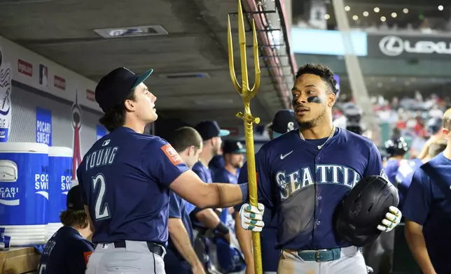 Seattle Mariners Jorge Polanco, right, is greeted by teammates as he holds a trident after hitting a home run during the eighth inning of a baseball game against the Los Angeles Angels Thursday, July 24, 2025, in Anaheim, Calif. (AP Photo/William Liang)