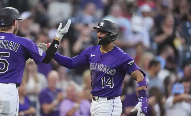 Colorado Rockies' Hunter Goodman, left, congratulates Ezequiel Tovar as he crosses home plate after hitting a two-run home run off Minnesota Twins relief pitcher Brock Stewart in the fifth inning of a baseball game Saturday, July 19, 2025, in Denver. (AP Photo/David Zalubowski)