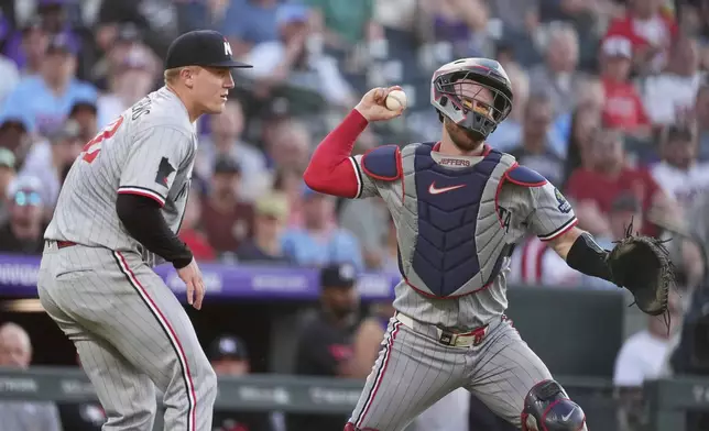 Minnesota Twins catcher Ryan Jeffers, right, looks to throw the ball to first base after fielding an infield single off the bat of Colorado Rockies' Jordan Beck as Twins starting pitcher Zebby Matthews, left, looks on in the third inning of a baseball game Saturday, July 19, 2025, in Denver. (AP Photo/David Zalubowski)