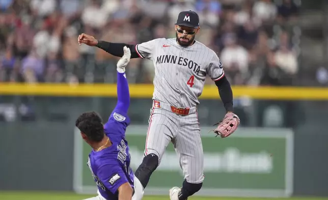 Minnesota Twins shortstop Carlos Correa, back, forces out Colorado Rockies' Ezequiel Tovar at second base on a ground ball hit by Michael Toglia in the seventh inning of a baseball game Saturday, July 19, 2025, in Denver. (AP Photo/David Zalubowski)