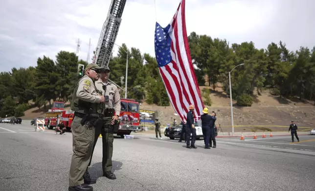 Sheriff's deputies stand along a procession route near where an explosion at a training facility killed three deputies on Friday, July 18, 2025, in Los Angeles. (AP Photo/Eric Thayer)