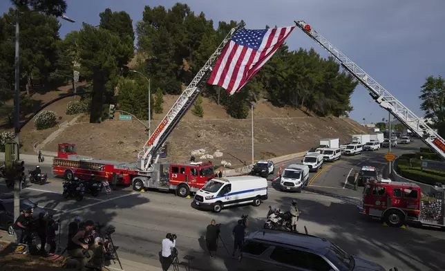 Medical examiner vans are driven along a procession route near where an explosion at a training facility killed three sheriff's deputies on Friday, July 18, 2025, in Los Angeles. (AP Photo/Eric Thayer)