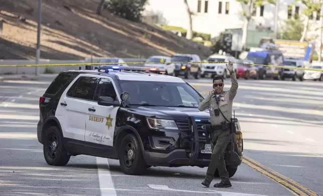 A sheriffs deputy monitors a street closure near the site of an explosion at the LA County Sheriff's Special Operations Bureau on Friday, July 18, 2025, in Los Angeles. (AP Photo/Etienne Laurent)