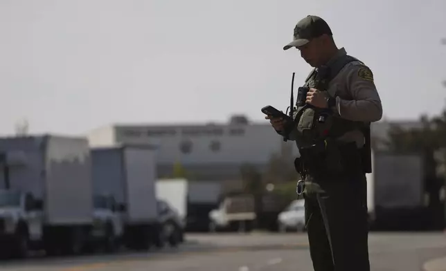 A sheriffs deputy monitors a street closure near the site of an explosion at the LA County Sheriff's Special Operations Bureau on Friday, July 18, 2025, in Los Angeles. (AP Photo/Etienne Laurent)