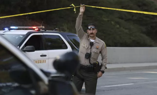 A sheriffs deputy monitors a street closure near the site of an explosion at the LA County Sheriff's Special Operations Bureau on Friday, July 18, 2025, in Los Angeles. (AP Photo/Etienne Laurent)