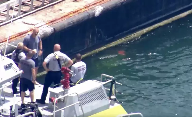 This image taken from video provided by WSVN-TV shows Miami-Dade Fire Rescue and others in a boat around what appears to be a barge involved in an accident with a group of kids and an adult on a sailing boat during a sailing camp, Monday, July 28, 2025, in Miami. (WSVN-TV via AP)