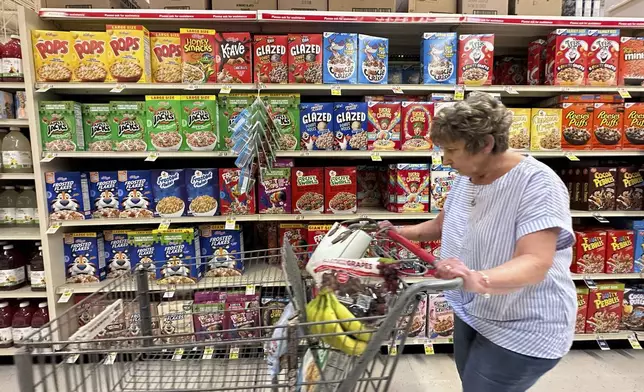 A woman pushes a shopping cart past boxes of Kellogg's breakfast cereal at a supermarket, Friday, July 11, 2025, in Springfield, Pa. (AP Photo/Matt Slocum)