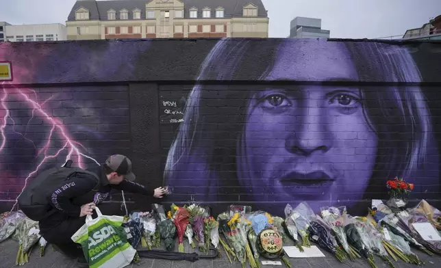 A fan lay flowers to commemorate the death of Ozzy Osbourne in Birmingham, Wednesday, July 23, 2025. (AP Photo/Kin Cheung)