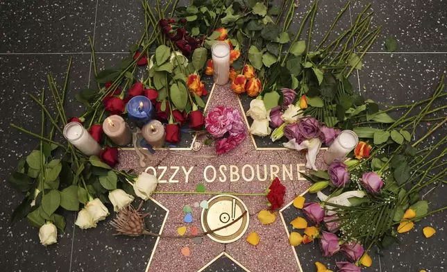 Flowers and candles are placed around the star for Ozzy Osbourne at the Hollywood Walk of Fame on Tuesday, July 22, 2025, in Los Angeles. (AP Photo/Damian Dovarganes)