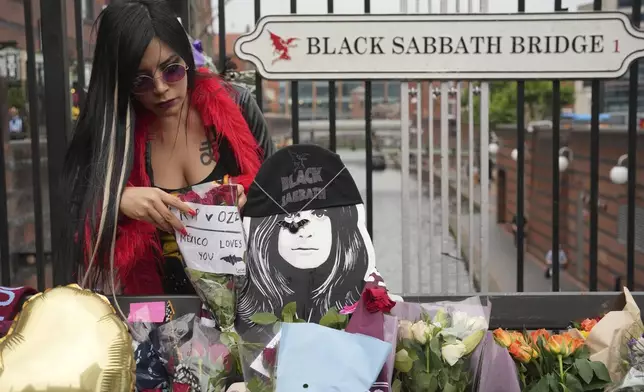 Lesley Venegas places flower to commemorate the death of Ozzy Osbourne at the Black Sabbath Bridge in Birmingham, Wednesday, July 23, 2025. (AP Photo/Kin Cheung)