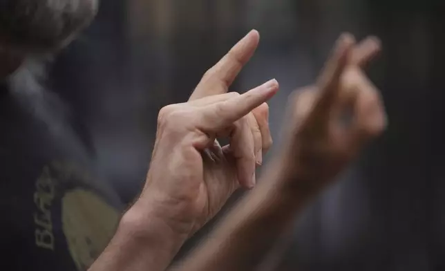 A music fan poses for a photograph to commemorate the death of Ozzy Osbourne at the Black Sabbath Bridge in Birmingham, Wednesday, July 23, 2025. (AP Photo/Kin Cheung)