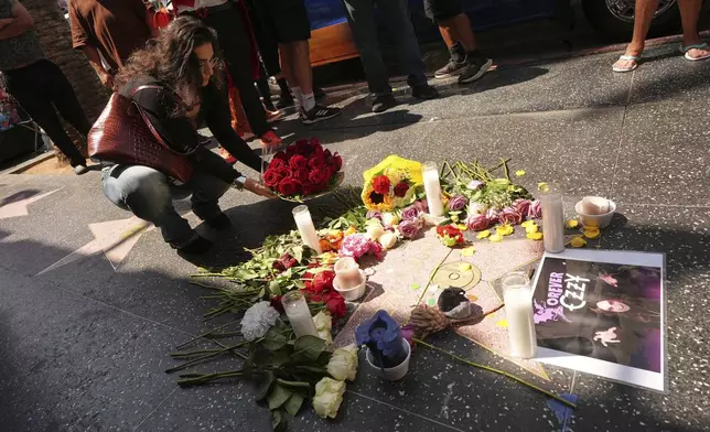 Julia Simonyan places flowers at the star for Ozzy Osbourne on the Hollywood Walk of Fame, Tuesday, July 22, 2025, in Los Angeles. (AP Photo/Damian Dovarganes)