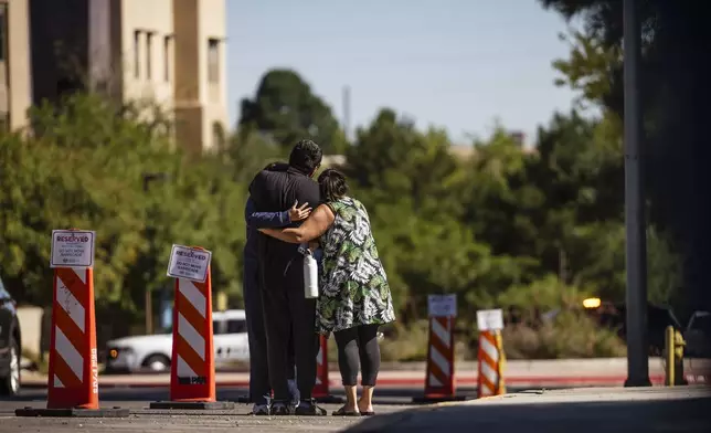 Family members embrace at the University of New Mexico Central Campus after a deadly shooting at Casas del Rio (Gila), a student housing center, early Friday, July 25, 2025 in Albuquerque, N.M. (Chancey Bush/The Albuquerque Journal via AP)