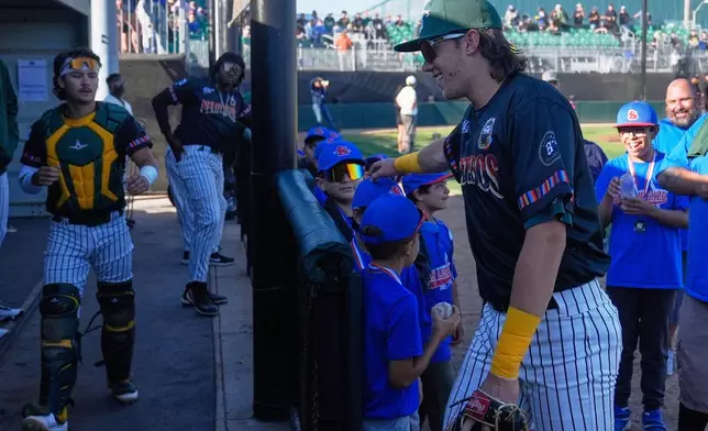 Oakland Ballers' Lou Helmig, foreground right, greets youth baseball players before a Pioneer League baseball game against the Rocky Mountain Vibes in Oakland, Calif., Thursday, July 10, 2025. (AP Photo/Jeff Chiu)