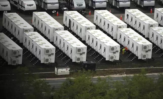 Workers sit alongside trailers as work progresses on a new migrant detention center dubbed "Alligator Alcatraz," at Dade-Collier Training and Transition facility in the Florida Everglades, Friday, July 4, 2025, in Ochopee, Fla. (AP Photo/Rebecca Blackwell)