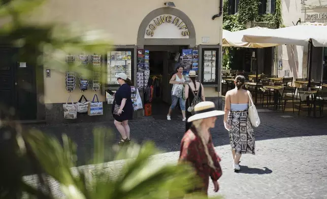 People walk past a souvenir shop in the town of Castel Gandolfo, a historic summer retreat for popes about 30 kilometers southeast of Rome, where Pope Leo XIV will be spending a short period of rest, is seen Wednesday, July 2, 2025. (AP Photo/Andrew Medichini)