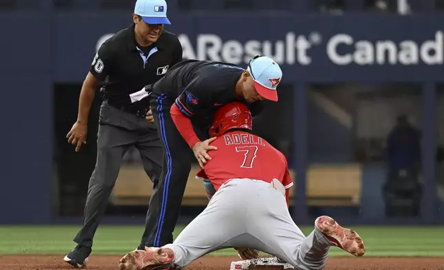 Los Angeles Angels' Jo Adell (7) slides safely into second base with a double ahead of a tag by Toronto Blue Jays second baseman Andres Gimenez, center, in fifth-inning baseball game action in Toronto, Friday, July 4, 2025. (Jon Blacker/The Canadian Press via AP)