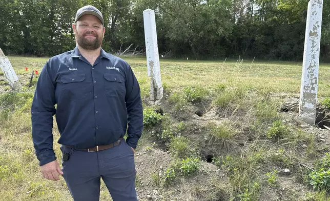 Joshua Herman, owner/operator of Herman Pest Control Services, poses for a photo on Monday, July 14, 2025, next to holes dug by Richardson's ground squirrels in Minot, N.D. (AP Photo/Jack Dura)