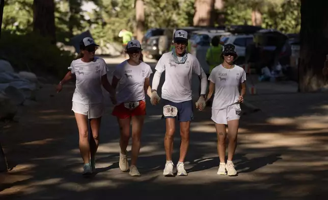 Danny Westergaard, second from right, nears the finish line of the Badwater 135 Ultramarathon beside daughters Meagan Westergaard, right, Madison Westergaard, and cousin Jennifer Drain, left, Wednesday, July 9, 2025, at Whitney Portal near Lone Pine, Calif. (AP Photo/John Locher)