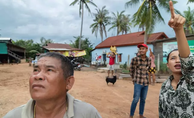 A resident of Samraong, the capital of Cambodia's Oddar Meanchey Province, points to where she sees an aircraft being fired at by Cambodian forces on Friday, July 25, 2025. (AP Photo/Anton L. Delgado)