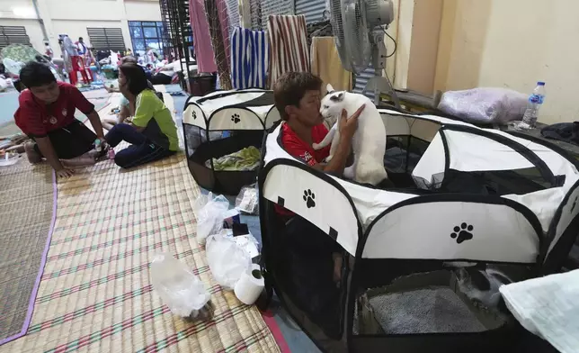 Pornpan Sooksai holds her cat named Kung Fu as residents who fled homes following clashes between Thai and Cambodian soldiers rest at an evacuation center in Surin province, Thailand, Friday, July 25, 2025. (AP Photo/Sakchai Lalit)