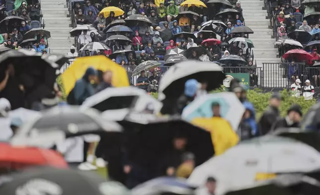 Spectators hold up umbrellas as heat rain falls during the first round of the British Open golf championship at the Royal Portrush Golf Club, Northern Ireland, Thursday, July 17, 2025. (AP Photo/Francisco Seco)