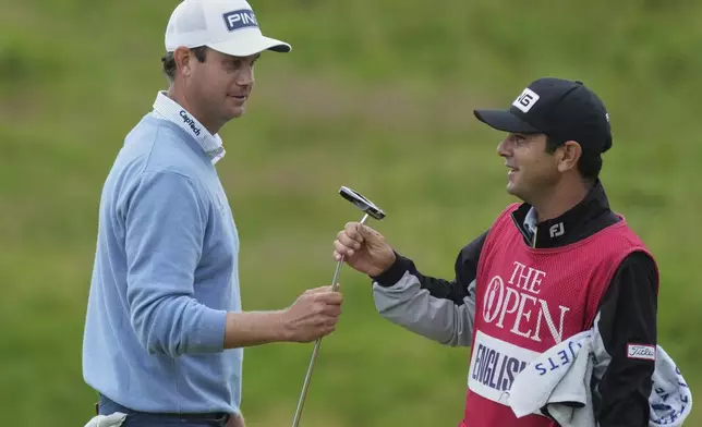 Harris English of the United States hands his club to his caddie Ramon Bescansa on the 11th green during the first round of the British Open golf championship at the Royal Portrush Golf Club, Northern Ireland, Thursday, July 17, 2025. (AP Photo/Jon Super)
