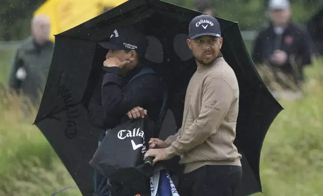 Xander Schauffele of the United States looks round as he shelters under an umbrella on the 2nd hole during the first round of the British Open golf championship at the Royal Portrush Golf Club, Northern Ireland, Thursday, July 17, 2025. (AP Photo/Jon Super)